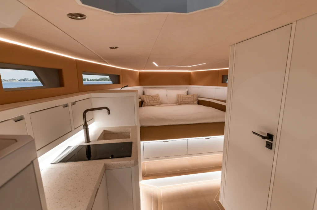 Modern luxury yacht interior with integrated kitchen and cozy bed, showcasing refined yacht interior construction with meticulous lighting and detailing.